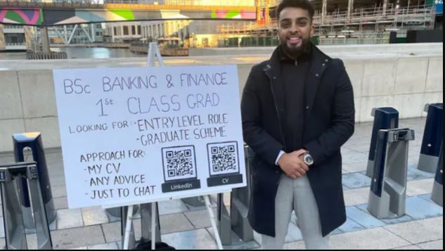 London Job Seeker Stood In Station With Placard CV For Job